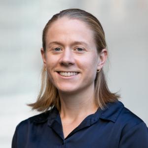 A photo of a white woman with blond hair. She is smiling and wearing a dark blue shirt.