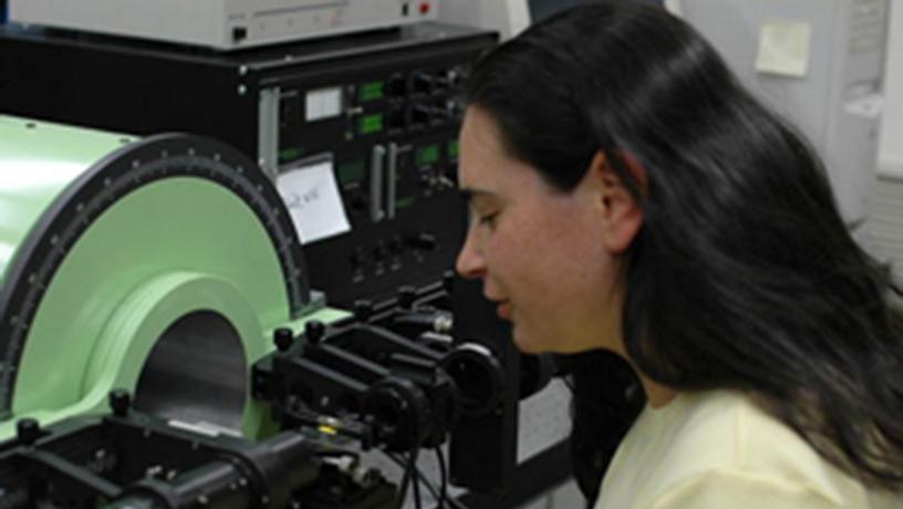 A graduate student in Materials Science & Engineering performs research on a machine in a lab