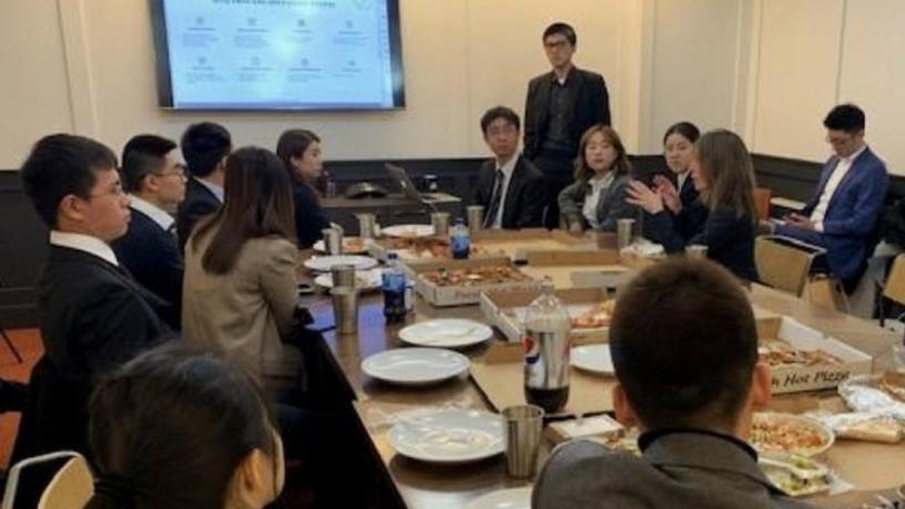 Students sitting around a table listening to a representative from  MSQ Ventures headquarters talk about their company