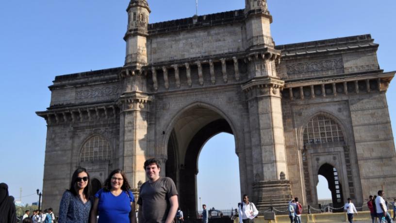 Three people standing infront of the Gateway of India