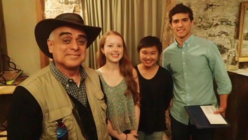 A professor stands with three students