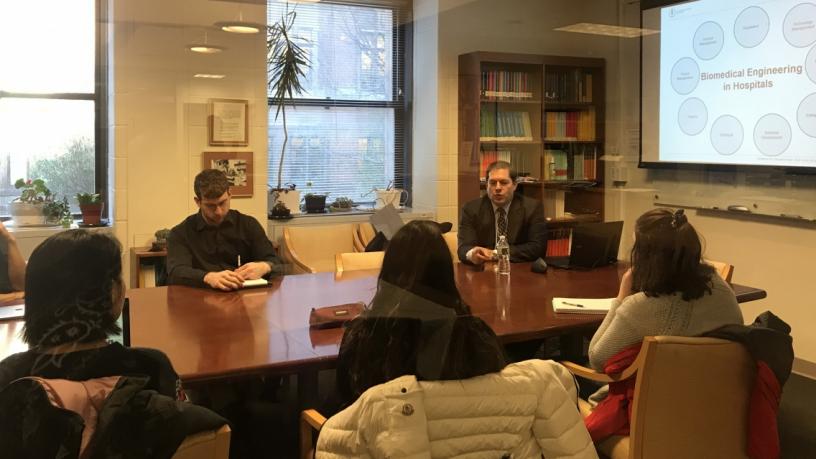 Five people sit around a conference room table looking at a projection screen