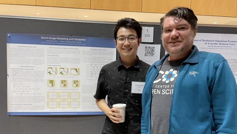 A student and a professor smiling and standing in front of a research poster. 