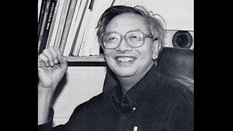 Photo of Prof. C.K. Chu sitting at his desk and laughing in 1986