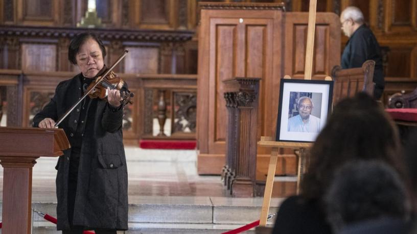 Dr. Yeou-Cheng Ma stands in the front of the chapel and plays violin