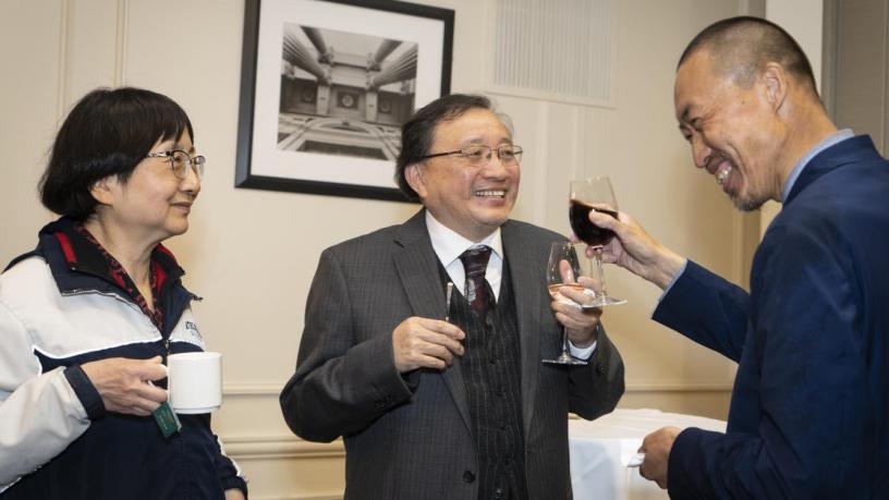 People stand at a reception and are talking and smiling.