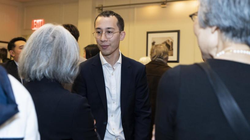 People stand at a reception and are talking and smiling.