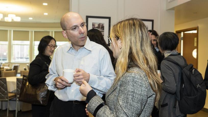 People stand at a reception and are talking and smiling.