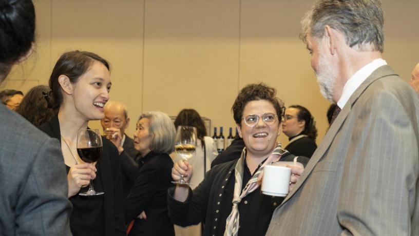 People stand at a reception and are talking and smiling.