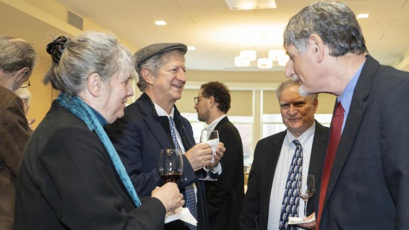 People stand at a reception and are talking and smiling.