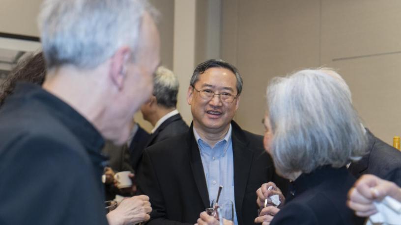 People stand at a reception and are talking and smiling.