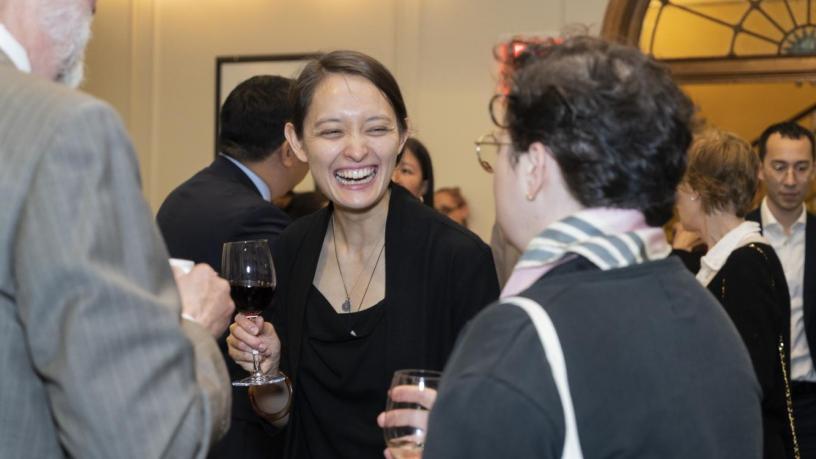 People stand at a reception and are talking and smiling.