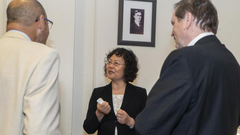 People stand at a reception and are talking and smiling.