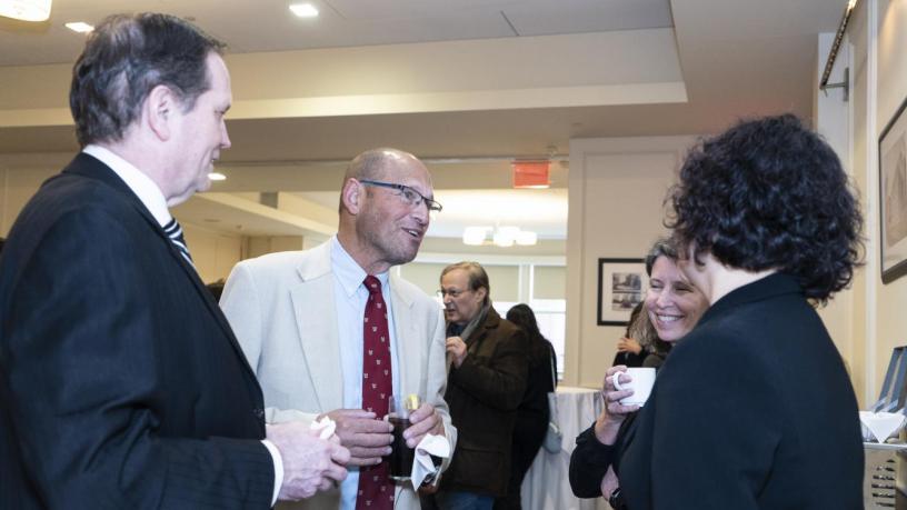 People stand at a reception and are talking and smiling.