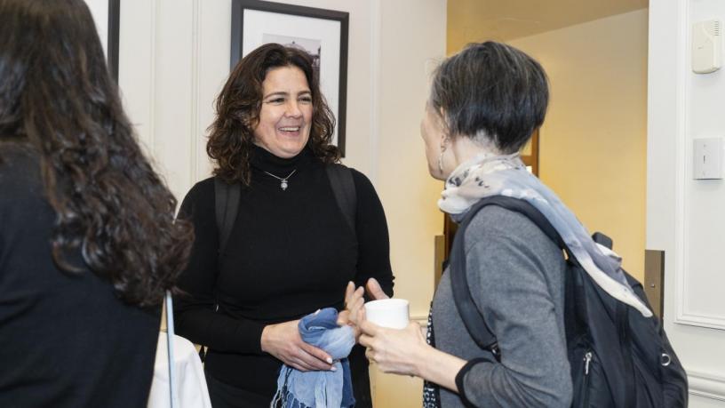 People stand at a reception and are talking and smiling.