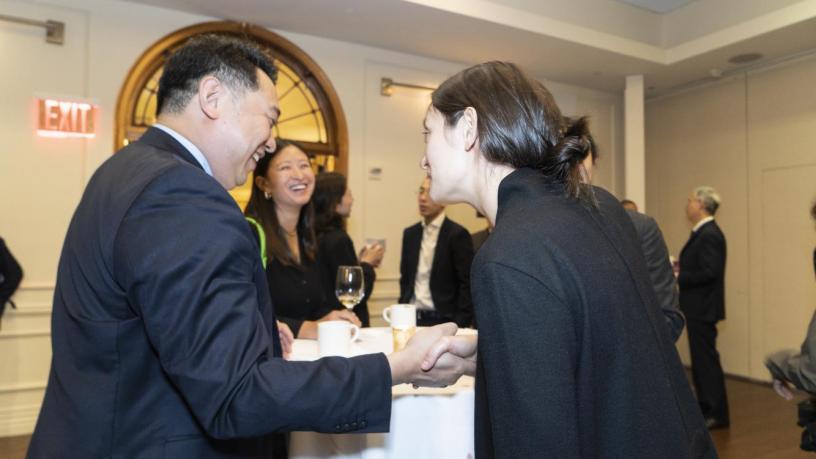 People stand at a reception and are talking and smiling.