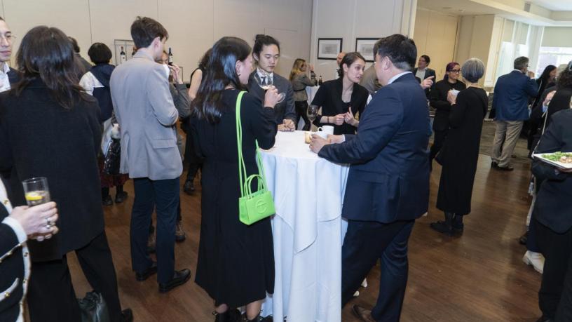 People stand at a reception and are talking and smiling.