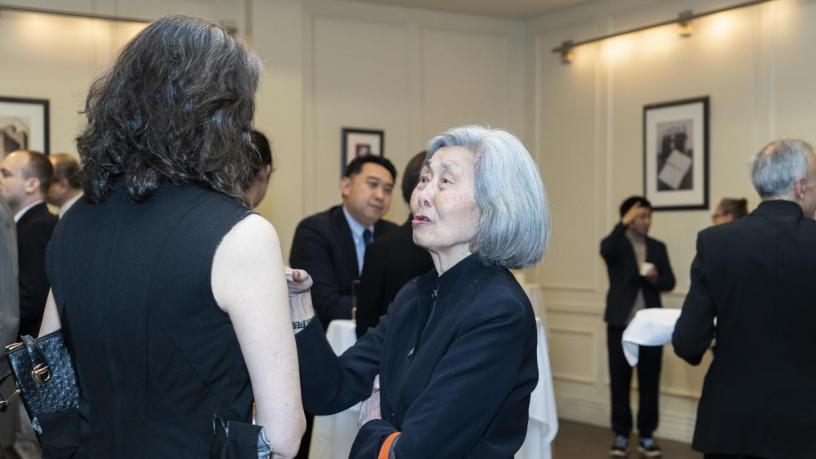 People stand at a reception and are talking and smiling.