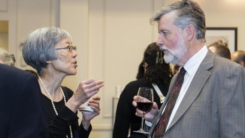 People stand at a reception and are talking and smiling.