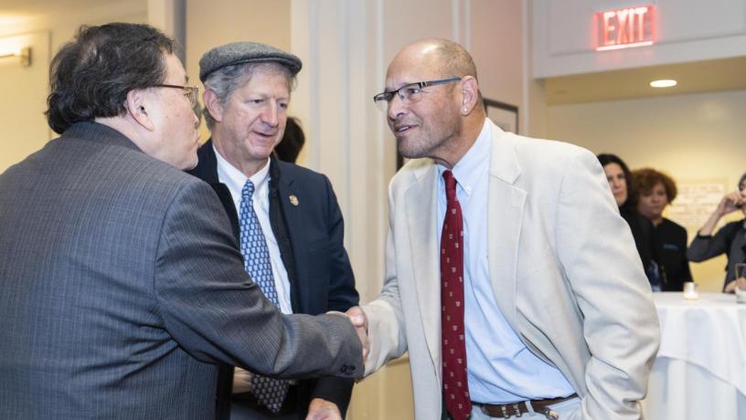 People stand at a reception and are talking and smiling.