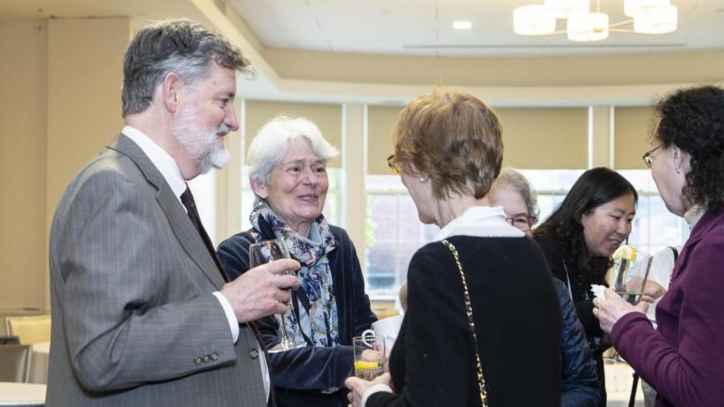 People stand at a reception and are talking and smiling.