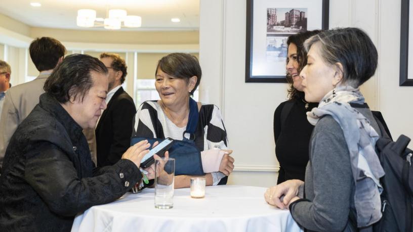 People stand at a reception and are talking and smiling.