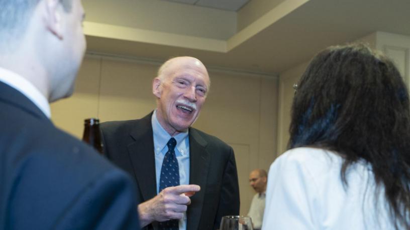 People stand at a reception and are talking and smiling.