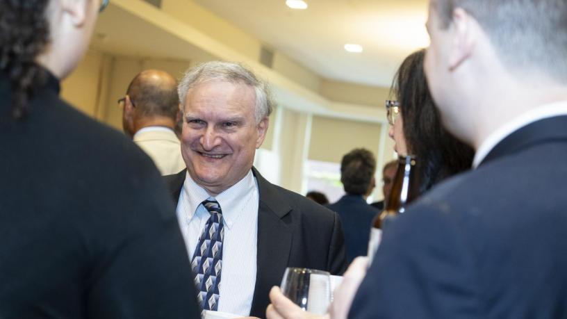 People stand at a reception and are talking and smiling.