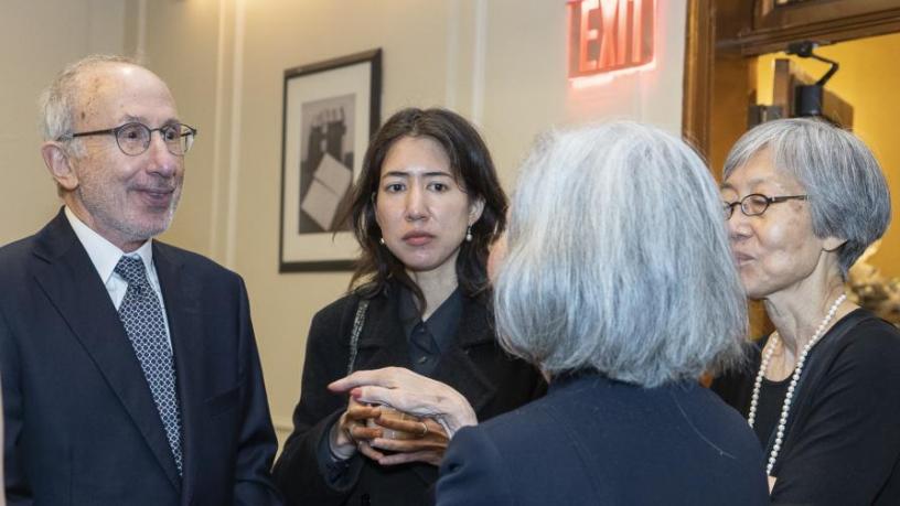 People stand at a reception and are talking and smiling.