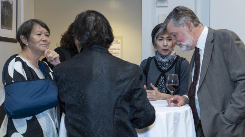 People stand at a reception and are talking and smiling.