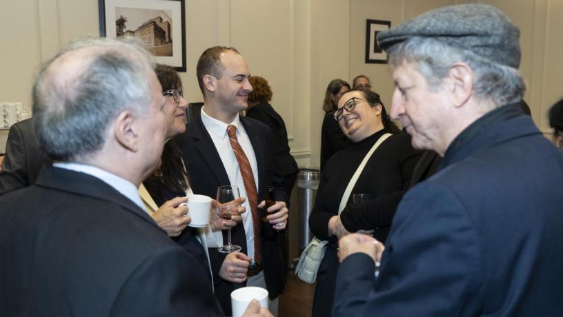 People stand at a reception and are talking and smiling.