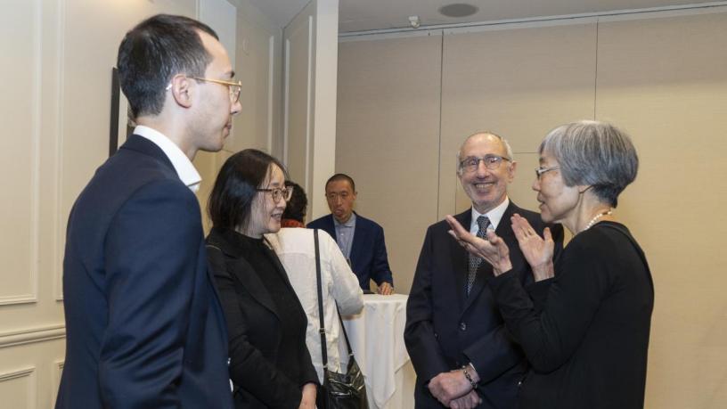 People stand at a reception and are talking and smiling.