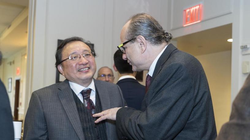 People stand at a reception and are talking and smiling.