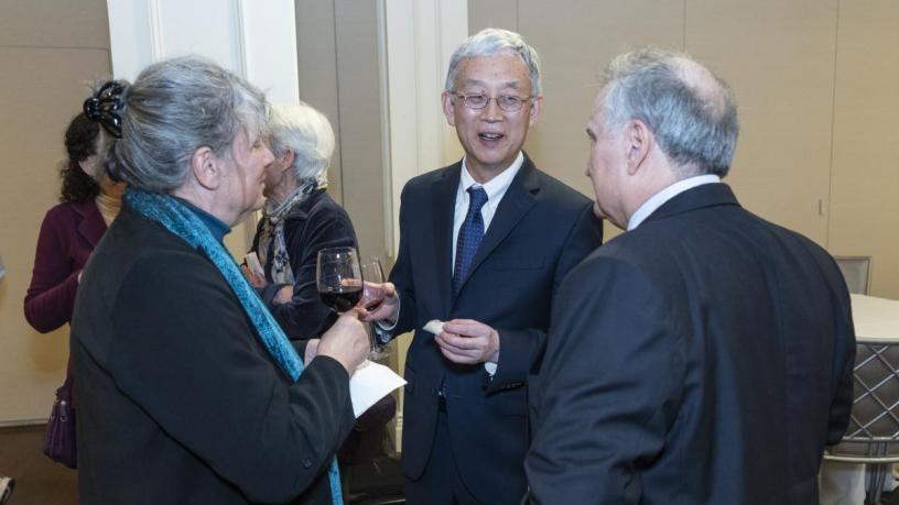 People stand at a reception and are talking and smiling.