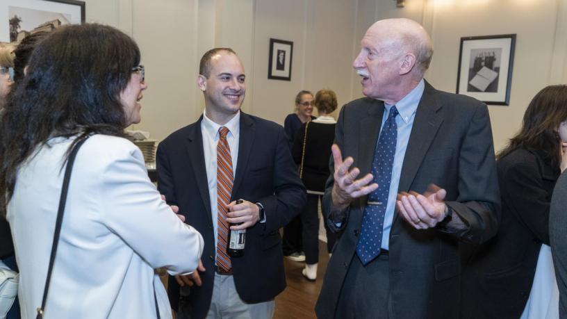 People stand at a reception and are talking and smiling.