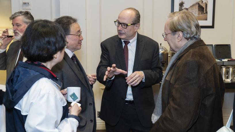 People stand at a reception and are talking and smiling.