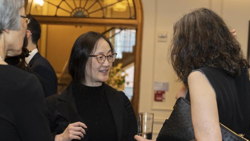 People stand at a reception and are talking and smiling.