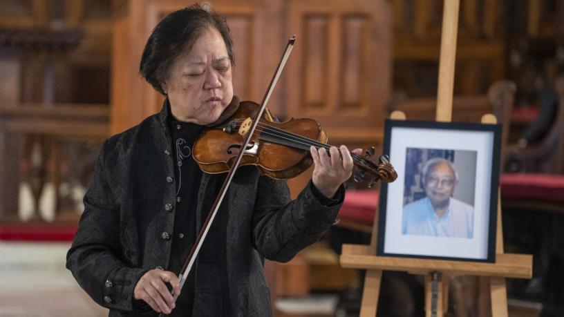 Dr. Yeou-Cheng Ma stands in the front of the chapel and plays violin