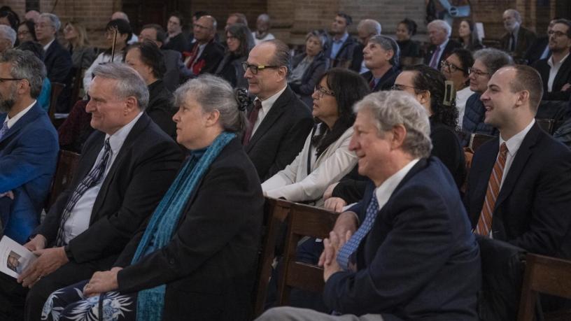 People sit in the chapel and face the podium.