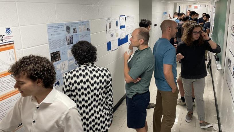 Several students stand in a hallway discussing research posters