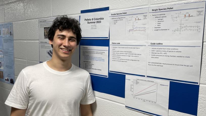 A student stands in front of their research poster