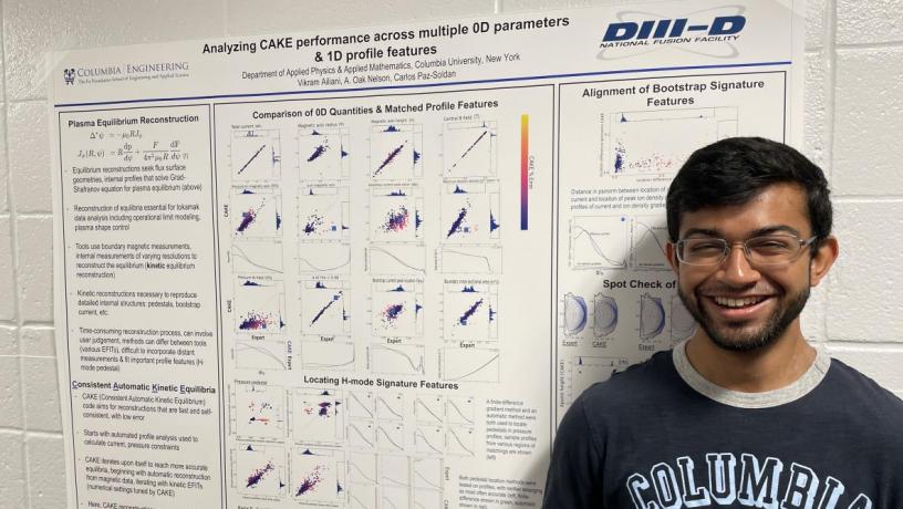 A student stands in front of their research poster