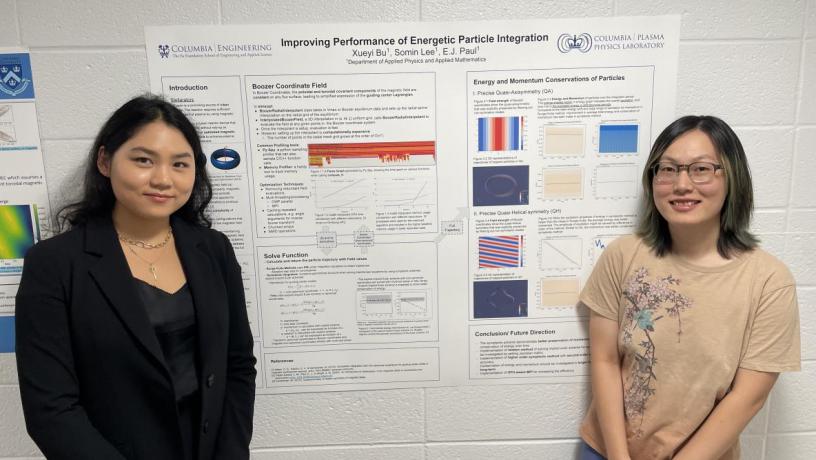 Two female students stand in front of their research poster