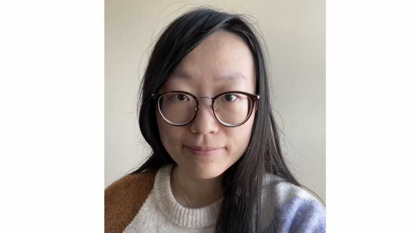 A photo of a woman. She is wearing glasses and looking at the camera.