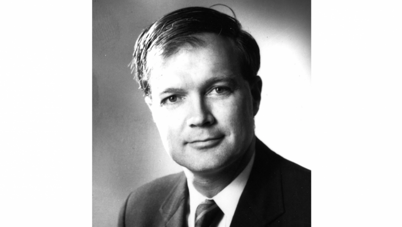 A black and white photo of a middle aged white man wearing a suit coat and tie