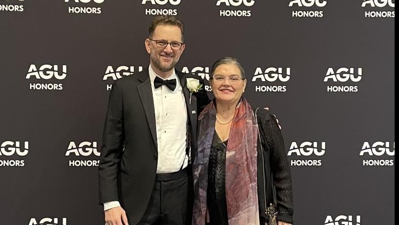 Two people (a man and a woman) stand in front of a background that says "AGU Honors". They are dressed in formal wear.
