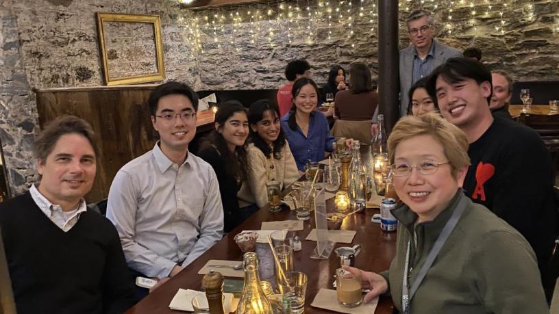students and faculty sit around a dining room table in a restaurant