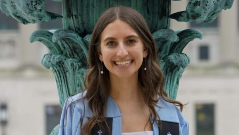 A photo of a young woman wearing light blue commencement regalia
