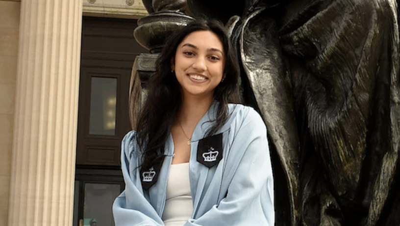 A photo of a young woman wearing light blue commencement regalia
