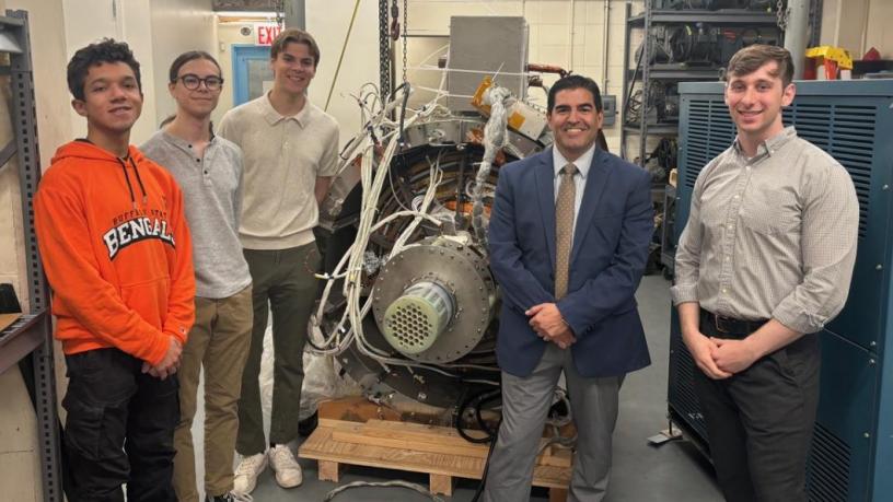 A group of college students and a middle aged man stand in a lab